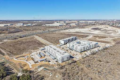 A large building complex is under construction in a barren landscape. at ThreeTwenty at the Vybe Apartments, Kyle, Texas