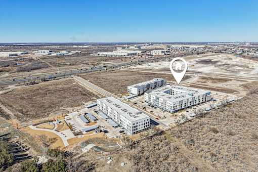 An aerial view of a construction site with a building and a parking lot. at ThreeTwenty at the Vybe Apartments, Texas