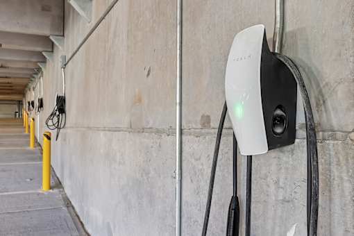 A white and black electric vehicle charging station with a green light on.