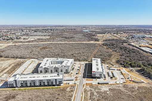 An aerial view of a large building complex surrounded by a barren landscape. at ThreeTwenty at the Vybe Apartments, Texas, 78640