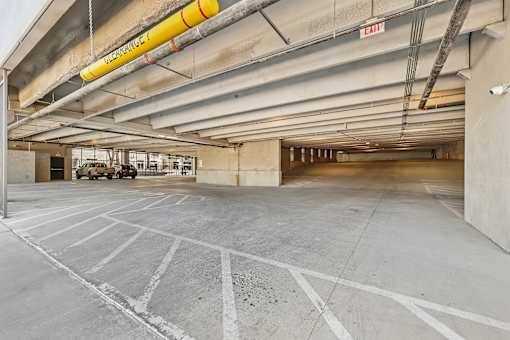 A large, empty parking garage with a yellow sign hanging from the ceiling.