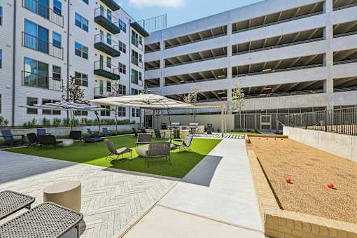 A patio area with a table and chairs is surrounded by apartment buildings.