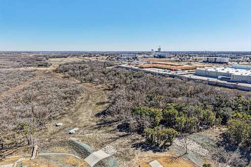 A barren landscape with a few trees and buildings in the distance. at ThreeTwenty at the Vybe Apartments, Texas