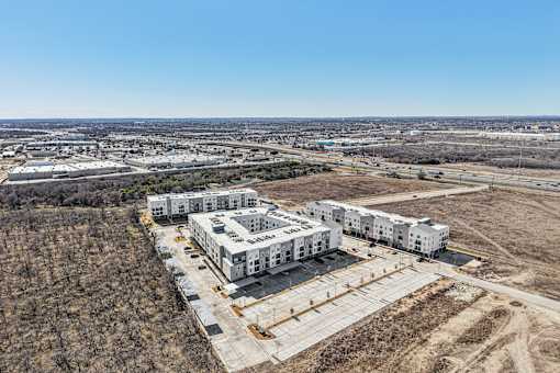 A large white building complex is under construction in a hilly area. at ThreeTwenty at the Vybe Apartments, Kyle, Texas