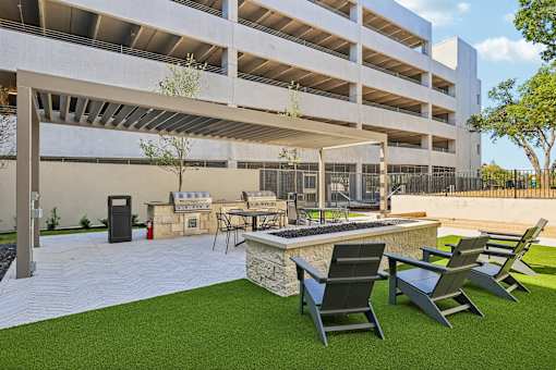 A patio area with chairs and a table in front of a parking garage.