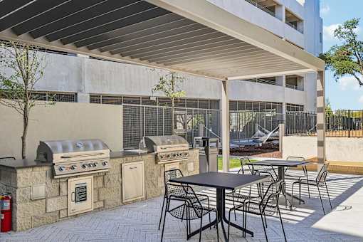 A patio with a table and chairs and a grill.