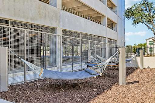 A hammock is strung between two poles in front of a concrete building.