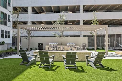 A patio with chairs and a table with a tablecloth and a bottle on it.
