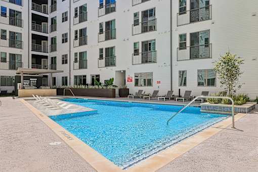 A swimming pool in front of a white apartment building.