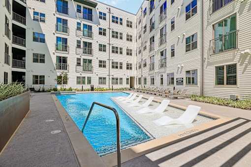 A swimming pool in front of a white building with a metal railing.