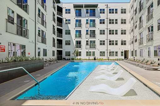 A swimming pool in front of apartment buildings with a "4 IN NO DIVING" sign.