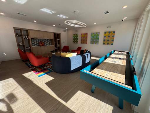 A room with a pool table and a shelf with books and a couch. at ThreeTwenty at the Vybe Apartments, Kyle, TX, 78640