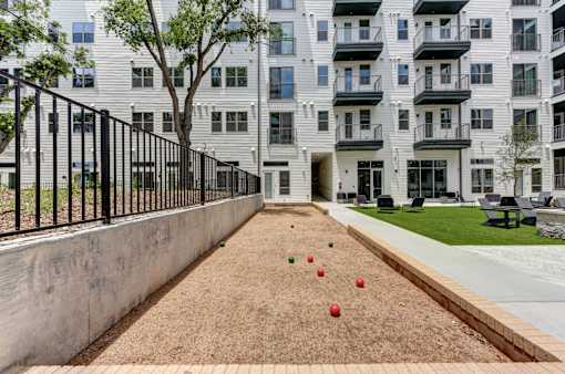 A sand pit with red and green balls in front of a building.