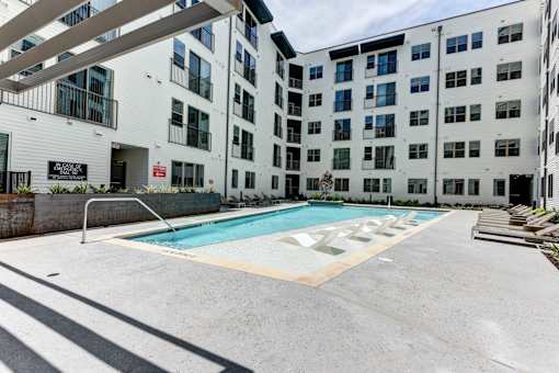 A swimming pool is located in the middle of a courtyard surrounded by buildings.