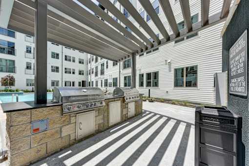 A patio with a grill and a wall with a sign.