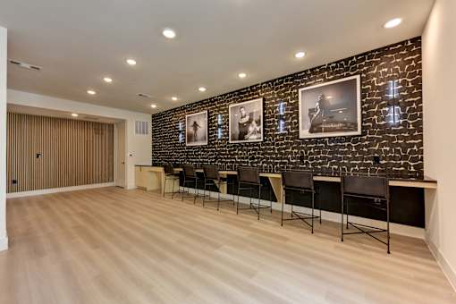 A room with a row of chairs and a brick wall with pictures on it.