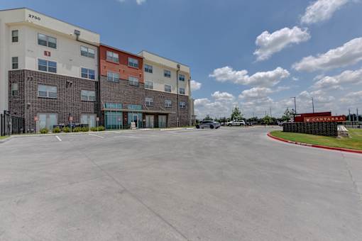 Building entrance with parking lot and driveway at Cantarra Apartments, Manor, TX