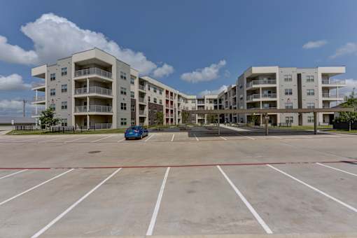 Four story apartment complex with front parking lot at Cantarra Apartments, Manor, 78653