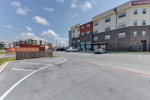 Entrance monument sign with parking and buildings at Cantarra Apartments, Texas, 78653