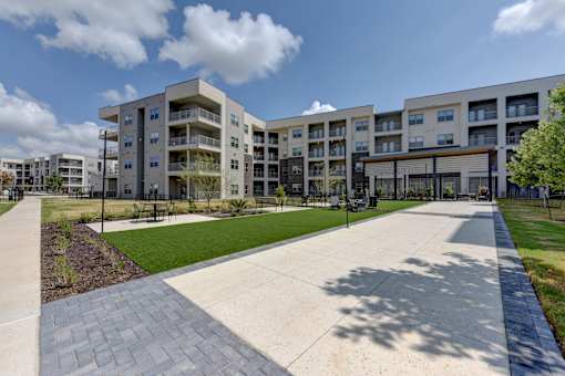 Courtyard with walking paths and lawn area at Cantarra Apartments, Texas, 78653