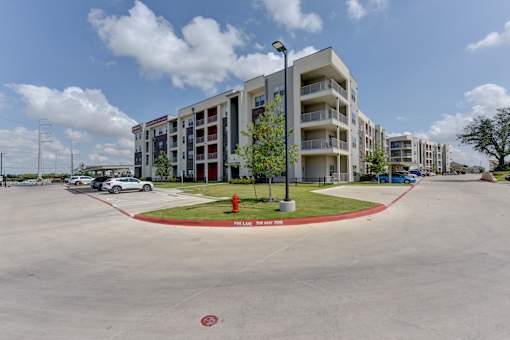Modern apartment complex with landscaped median at Cantarra Apartments, Manor, TX
