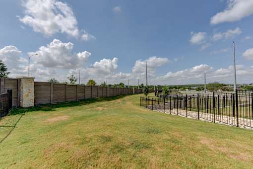 Perimeter fence with grassy open space and lighting at Cantarra Apartments, Manor, 78653