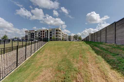 Sloped lawn area between fence and buildings at Cantarra Apartments, Texas
