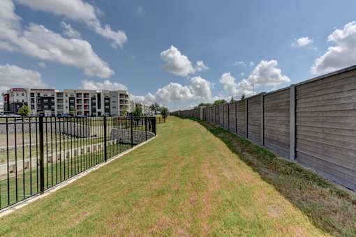 Grassy walking path between fencing and open field at Cantarra Apartments, Texas, 78653