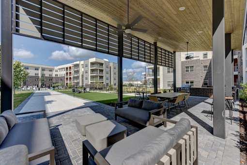 Covered outdoor patio with lounge furniture and ceiling fans at Cantarra Apartments, Manor