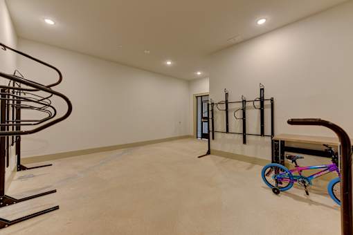 Home gym space with workout rig and spiral staircase at Cantarra Apartments, Texas