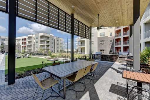 Covered outdoor dining area with grilling stations at Cantarra Apartments, Manor, TX