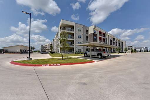 Modern apartment building with covered parking and carport at Cantarra Apartments, Manor, TX 78653