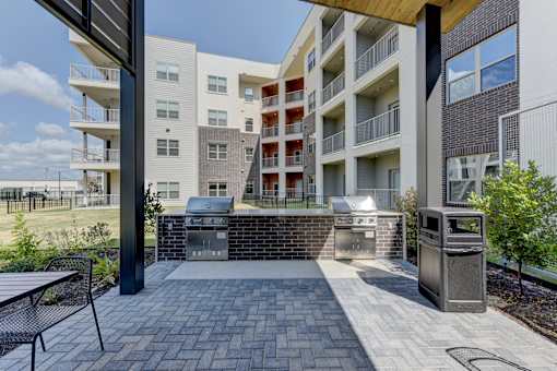 Outdoor grilling area with brick barbecue stations at Cantarra Apartments, Texas
