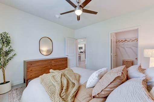 Bedroom with walk-in closet and wood furnishings at Cantarra Apartments, Texas