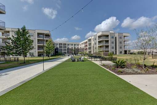Central courtyard with walkways and seating areas at Cantarra Apartments, Texas, 78653