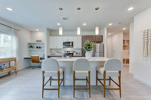 Modern kitchen with island seating and pendant lighting at Cantarra Apartments, Manor, TX 78653