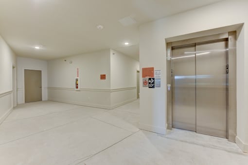 Elevator lobby with stainless steel doors and hallway at Cantarra Apartments, Texas, 78653
