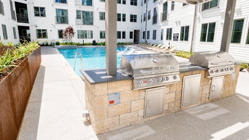 A poolside grill is in front of a white building.