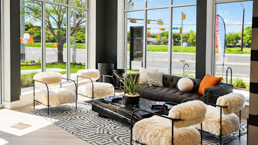 A black couch with white pillows and a plant on a black coffee table.