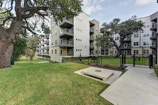 Courtyard green space with pathway and mature oak trees at Matador Apartments, Austin, TX