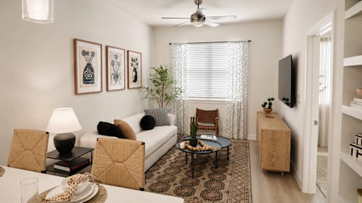 A living room with a white couch, a coffee table, and a ceiling fan.