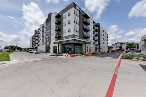 A large apartment building with a parking lot in front.