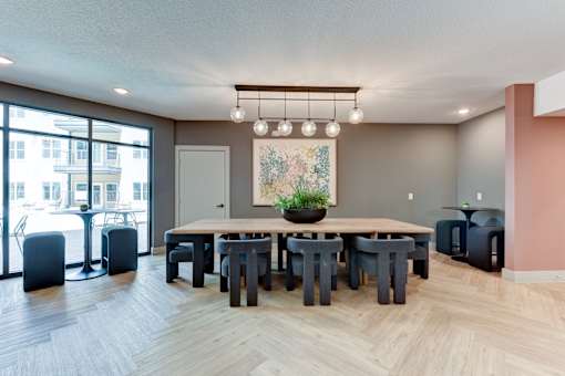 A dining room with a large table and chairs.