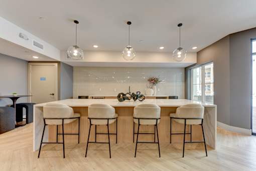 A modern kitchen with a bar area and four stools.