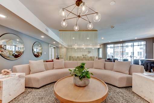 A living room with a large sectional sofa, a wooden coffee table, and a chandelier.