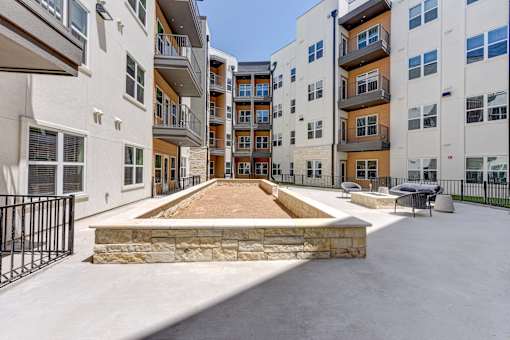 A courtyard surrounded by apartment buildings with a stone wall and a bench.