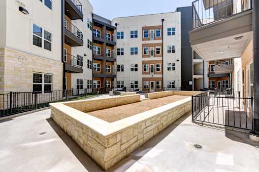 A courtyard with a sandpit surrounded by buildings.