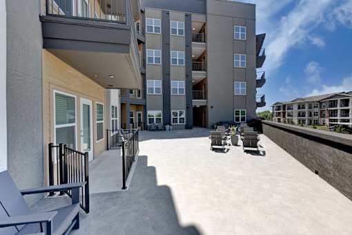 A modern apartment complex with a spacious courtyard and outdoor seating area.