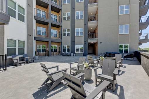 A patio area with chairs and tables in front of a building.