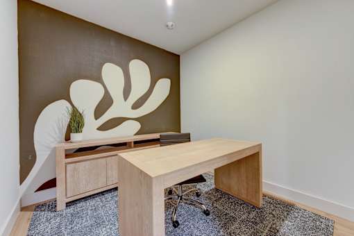 A room with a brown wall and a wooden desk with a plant on it.